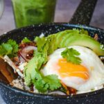 a bowl of food with an egg, avocado and rice